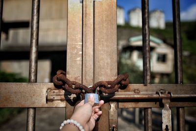 Close-up of hand holding rusty chain