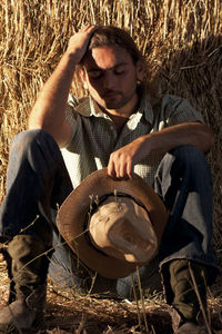 Man holding hat sitting on field