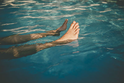 Low section of person swimming in pool