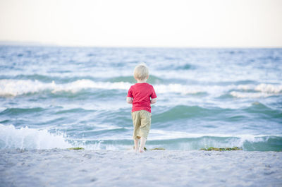 Rear view of blond boy standing at beach