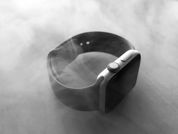 High angle view of smartwatch amidst smoke on table