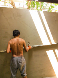 Rear view of shirtless worker working at construction site