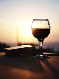 Close-up of wineglass on table against sky during sunset