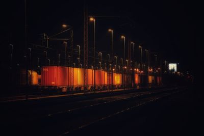 Illuminated road against sky at night