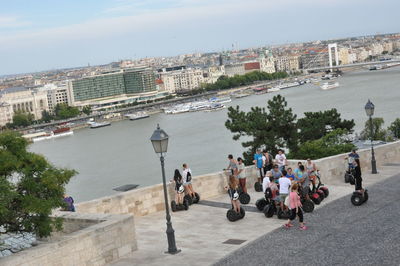 People on city by river against sky