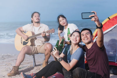 Young woman holding guitar on beach