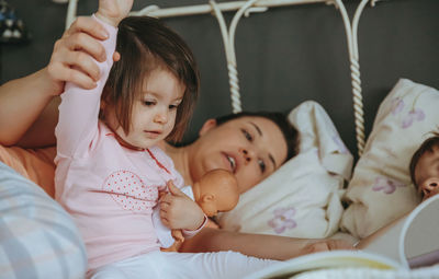 Close-up of mother telling bed time story to children on bed at home