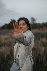 Portrait of young woman standing against sky