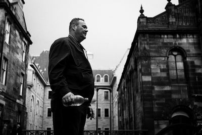 Low angle view of man looking away against buildings in city