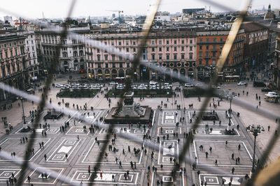 High angle view of people on piazza del duomo seen though chainlink fence