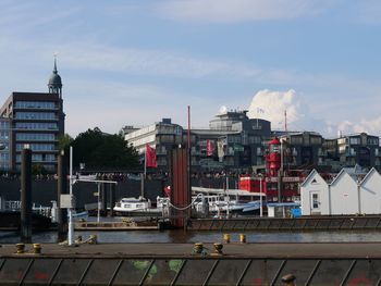 Boats moored at harbor against sky in city