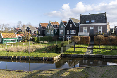 Houses by lake and buildings against sky