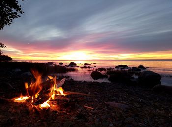 Bonfire on beach against sky during sunset