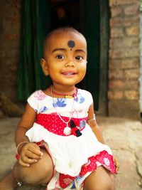 Portrait of cute baby girl smiling while sitting outside house