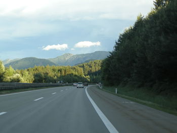 Cars on country road leading towards mountains