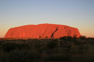 Scenic view of land against clear sky during sunset