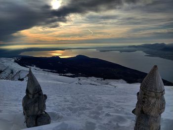 Scenic view of snow covered rocks against sky during sunset