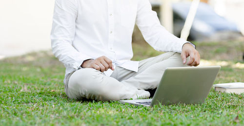 Rear view of man using mobile phone in grass