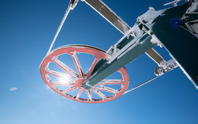 Frozen ski lift on a snowy mountain against blue sky.