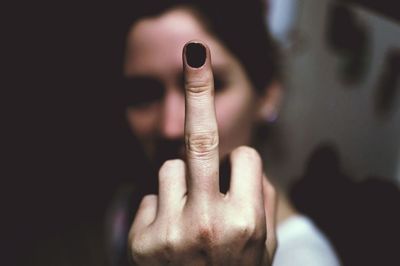 Close-up of woman showing obscene gesture at home