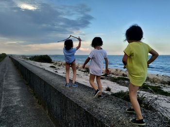 Full length of girls walking on retaining wall