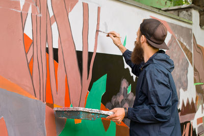 Side view of street artist painting on wall