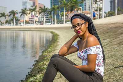 Portrait of young woman relaxing by sea on groyne