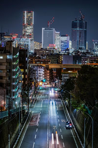 Illuminated street amidst buildings in city at night
