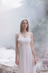 Beautiful young woman standing by river
