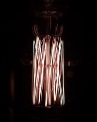 Close-up of illuminated light bulb against black background