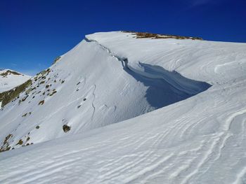 Low angle view of snowcapped mountain against clear blue sky
