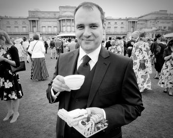 Portrait of smiling man holding food during party in lawn