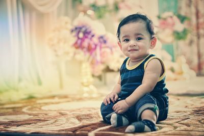 Portrait of cute boy sitting on carpet