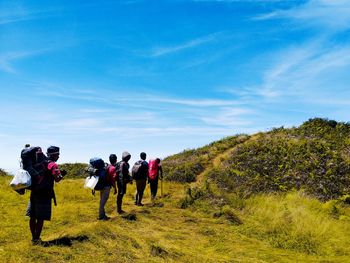 People walking on mountain against blue sky