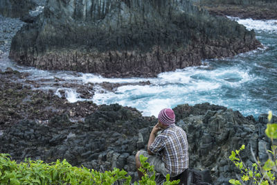 High angle view of man sitting on rocky shore