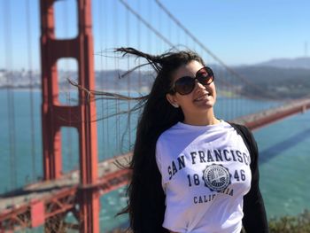 Portrait of young woman smiling against golden gate bridge