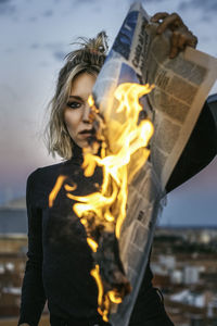 Blonde woman burning a newspaper.