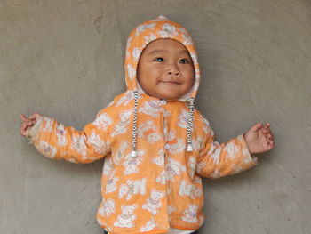 Close-up portrait of smiling girl standing against wall