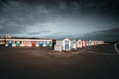 Beach huts by buildings against sky during sunset