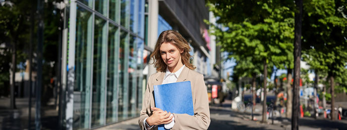 Portrait of young woman standing in city