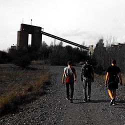 Rear view of people standing on bridge against sky