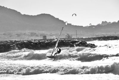 Person paragliding over sea with mountain in background