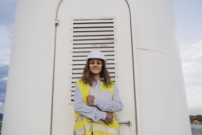 Portrait of young woman standing against wall