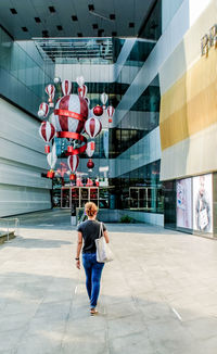 Full length rear view of two people walking in building