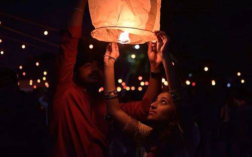 Midsection of young woman with illuminated lantern at night