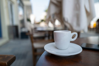 An espresso cup on a small bistro table in a pedestrian zone.