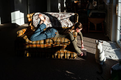 Teenage girl laying on the couch reading a book