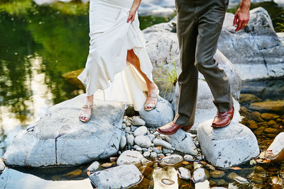 Low section of people standing on rock by lake