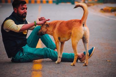 Full length of man eating dog