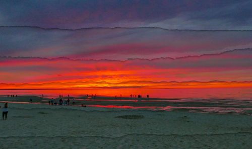 Scenic view of beach against dramatic sky during sunset